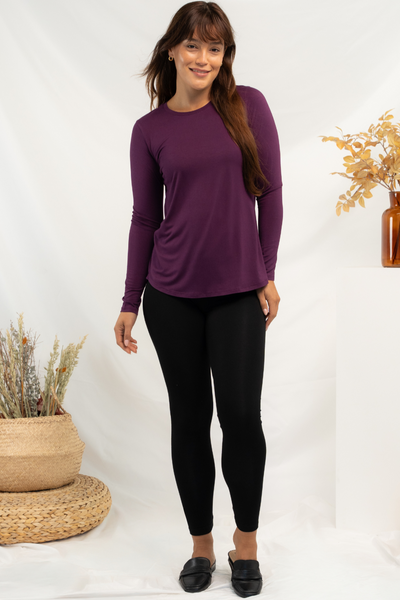 Model wearing a bamboo long sleeve top with crew neckline paired with black leggings and slip on loafer shoes.