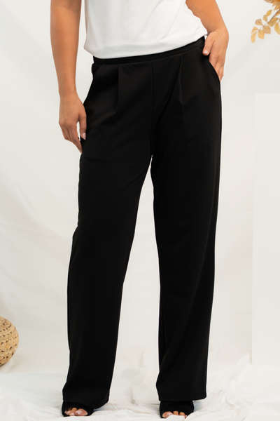 Close up of a woman wearing black pleated dress pants styled with mule heels and a white t-shirt.