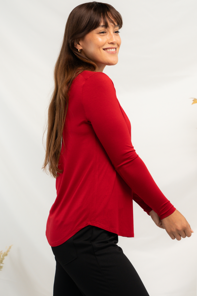 Side view of a red bamboo long sleeve top with curved hemline.