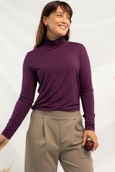 Woman wearing a turtleneck top in purple. 