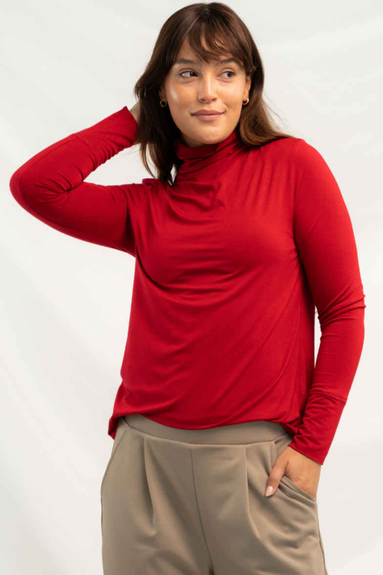 Model wearing a red funnel-neck long sleeve top paired with khaki pants.
