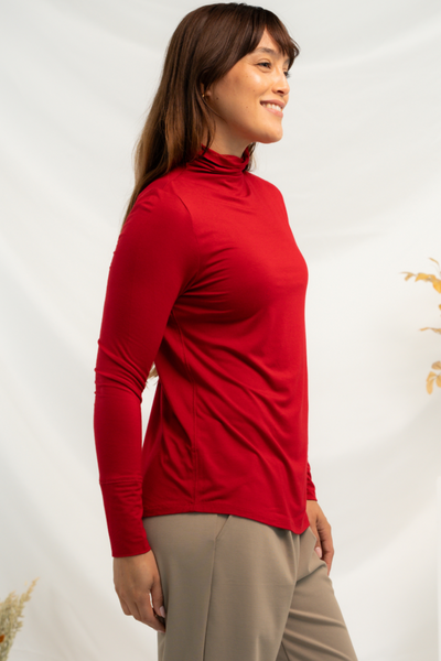 Side view of a red long sleeve top with funnel-neck and curved hemline.