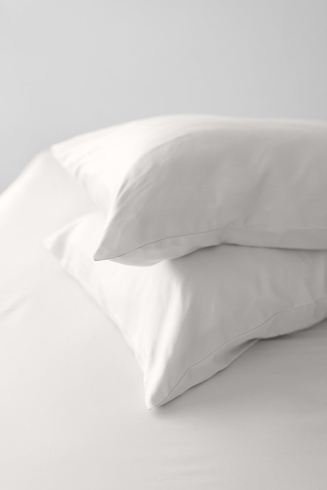 Two warm white pillows on a light gray background