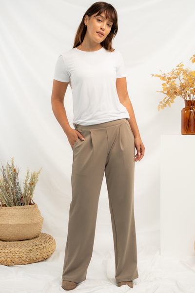 Woman wearing a white t-shirt and khaki pants standing against a white background with decorative fall elements.