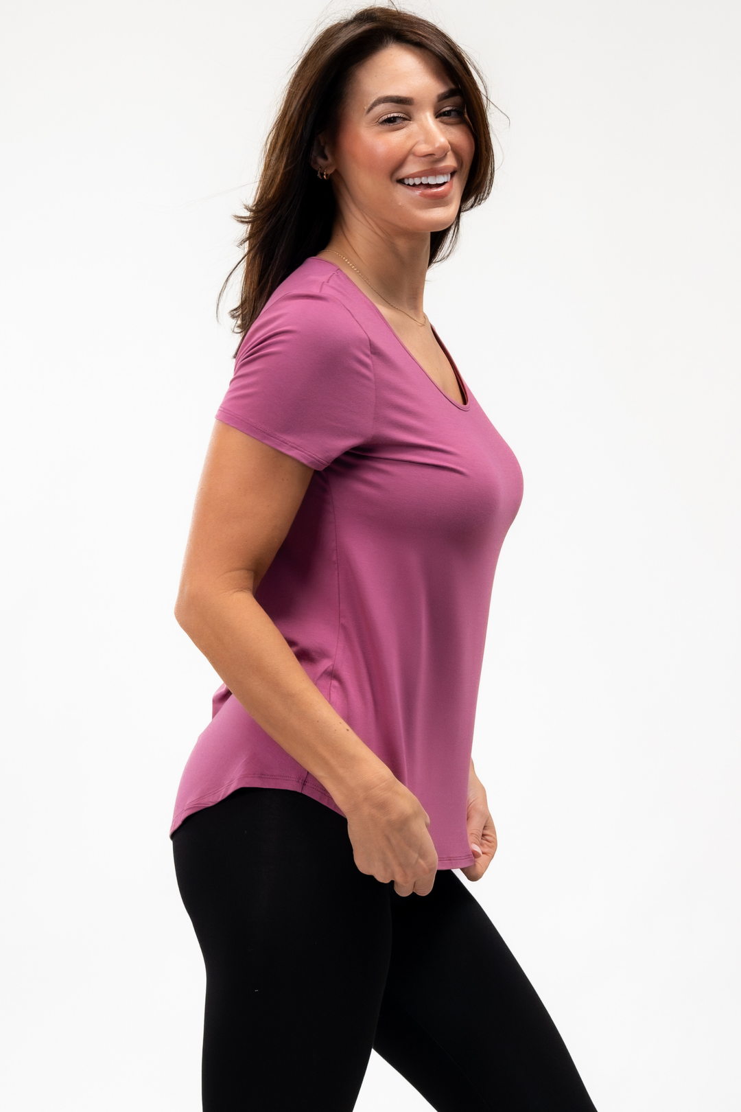 Woman wearing a pink bamboo t-shirt on a white background showing the side view with high low hem