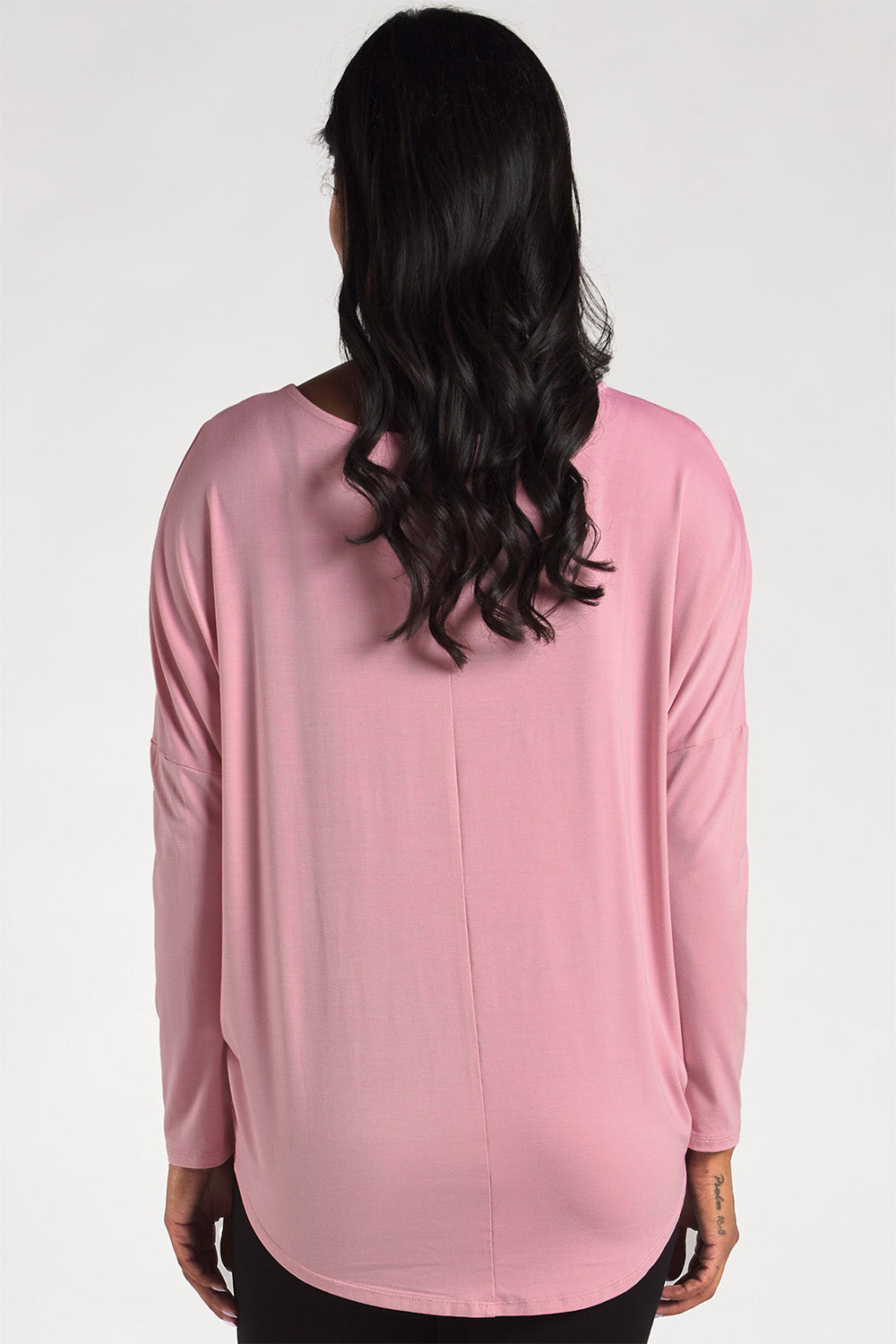 Back view of a woman styling a pink dolman sleeve bamboo top by Terrera.