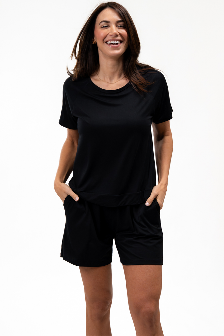 Woman wearing a black pajama short set on a white background