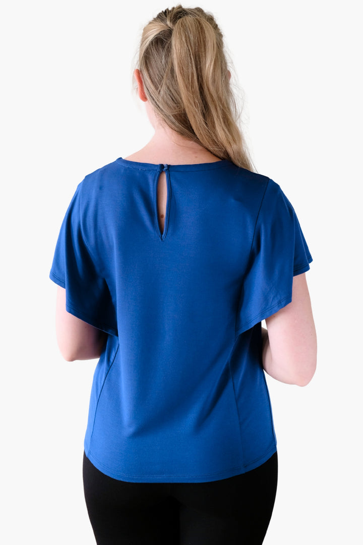 A woman wearing a blue top with ruffled sleeves 