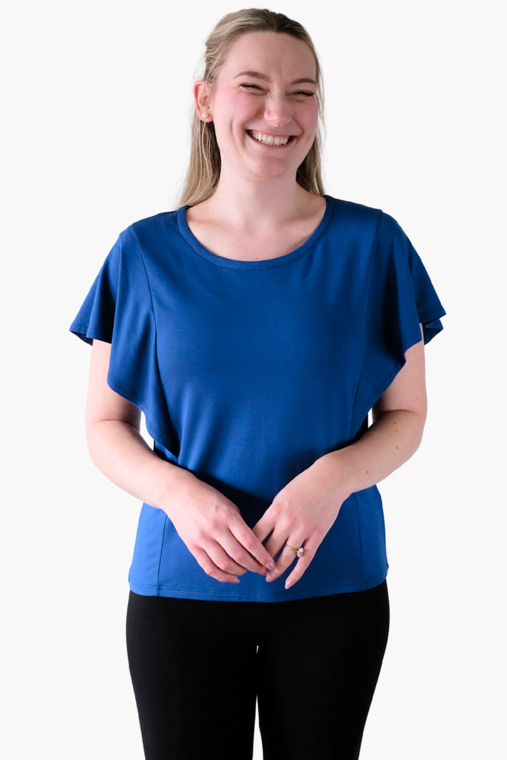 A woman wearing a blue top with ruffled sleeves 