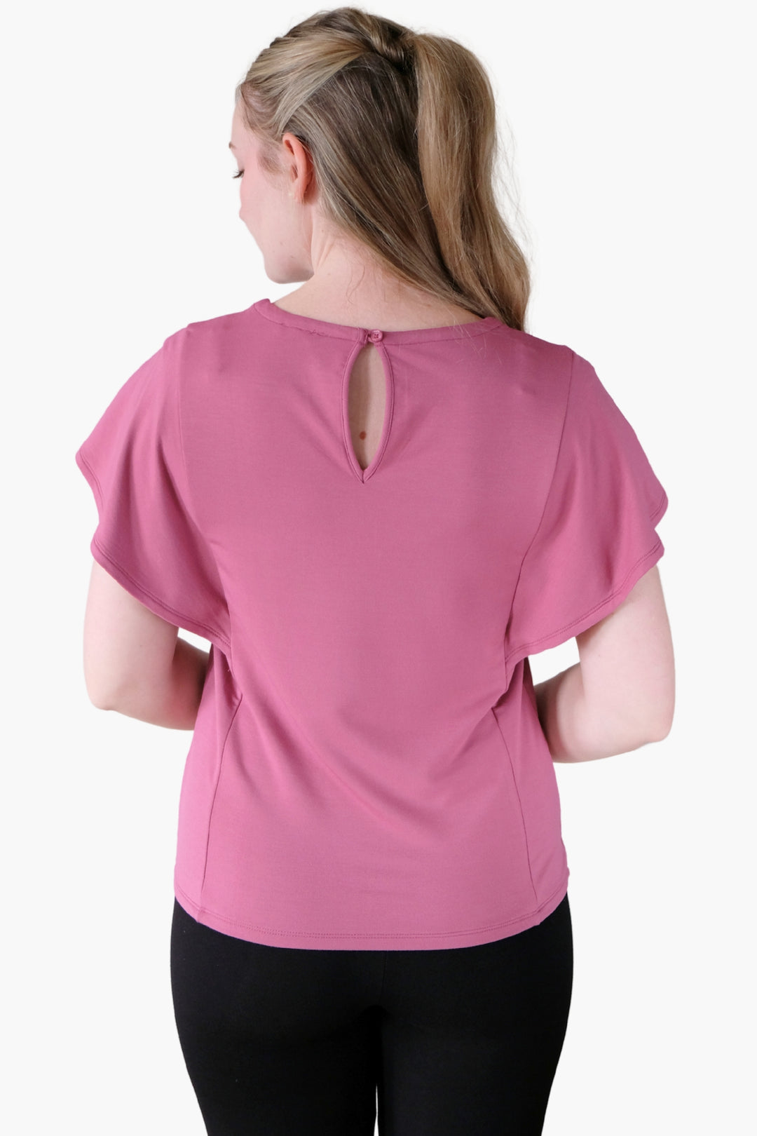 A woman wearing a pink flutter sleeve top made from bamboo