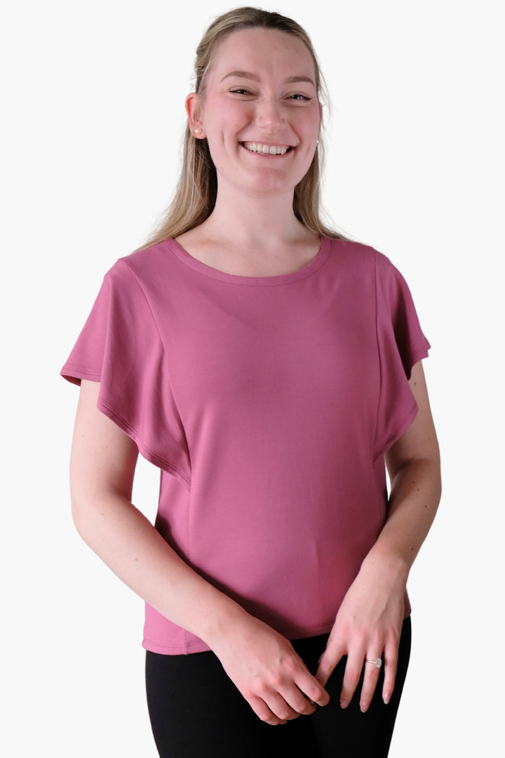 A woman wearing a pink flutter sleeve top made from bamboo