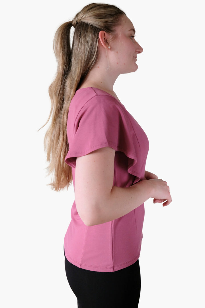 A woman wearing a pink flutter sleeve top made from bamboo