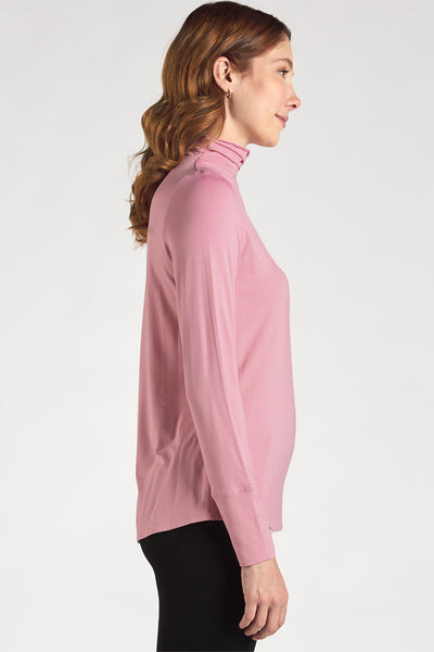 Side view of woman styling a Pink long sleeve funnel-neck top by Terrera.