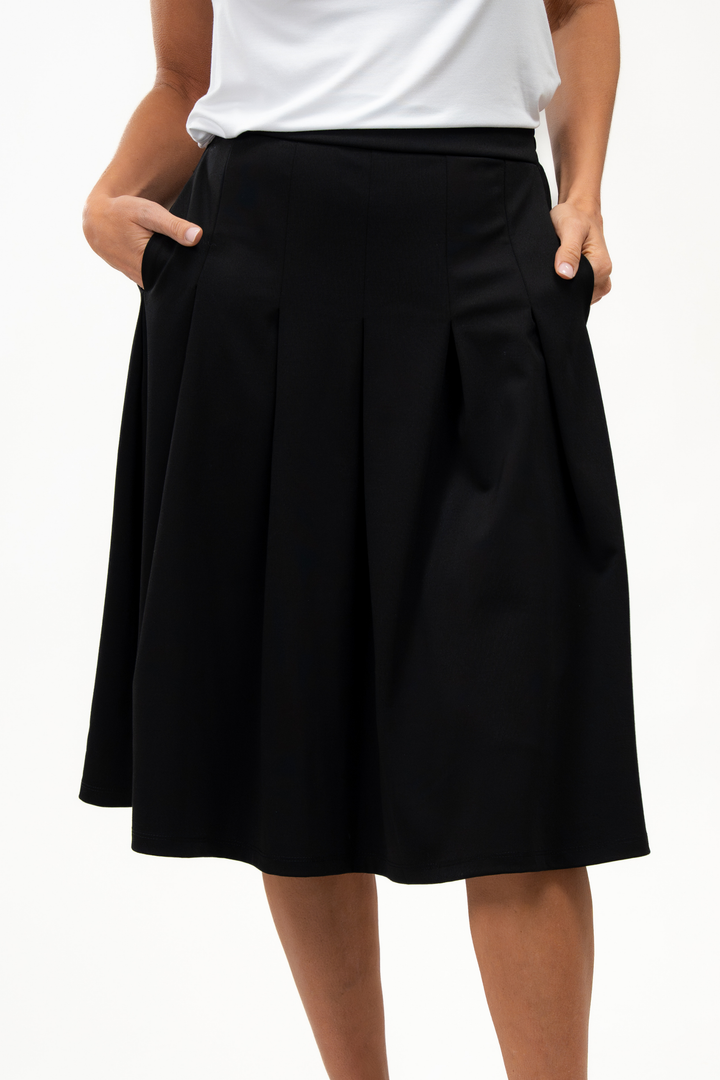Woman wearing a white t-shirt and black pleated skirt on a white background, showing the pocket details