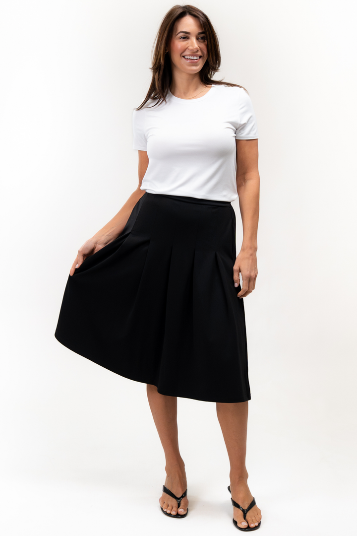 Woman wearing a white t-shirt and black pleated skirt on a white background