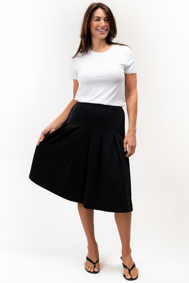 Woman wearing a white t-shirt and black pleated skirt on a white background