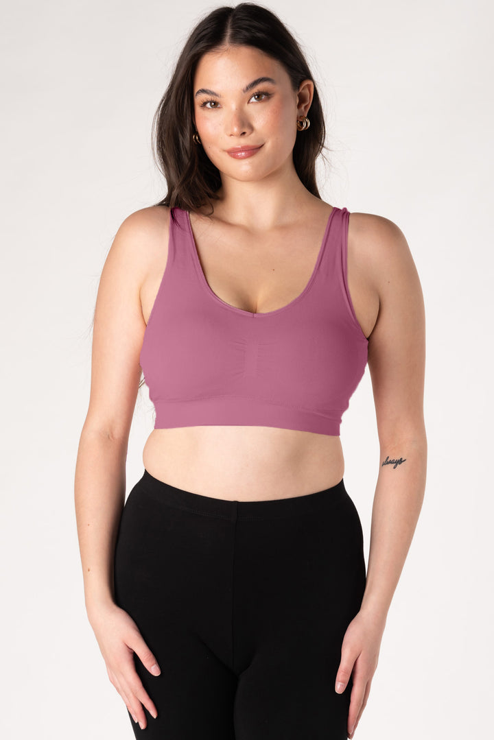 Woman wearing a dark pink bamboo bralette and black leggings on a white background