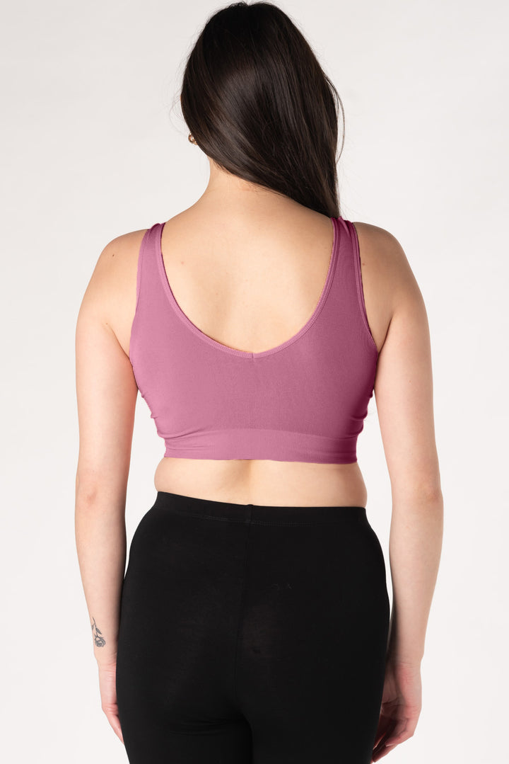 Woman wearing a dark pink bamboo bralette and black leggings on a white background showing the back v-neck style.