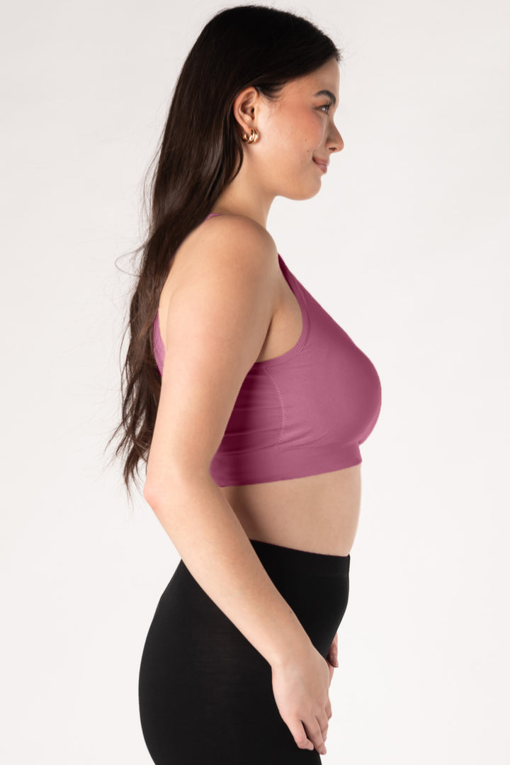 Woman wearing a dark pink bamboo bralette and black leggings on a white background