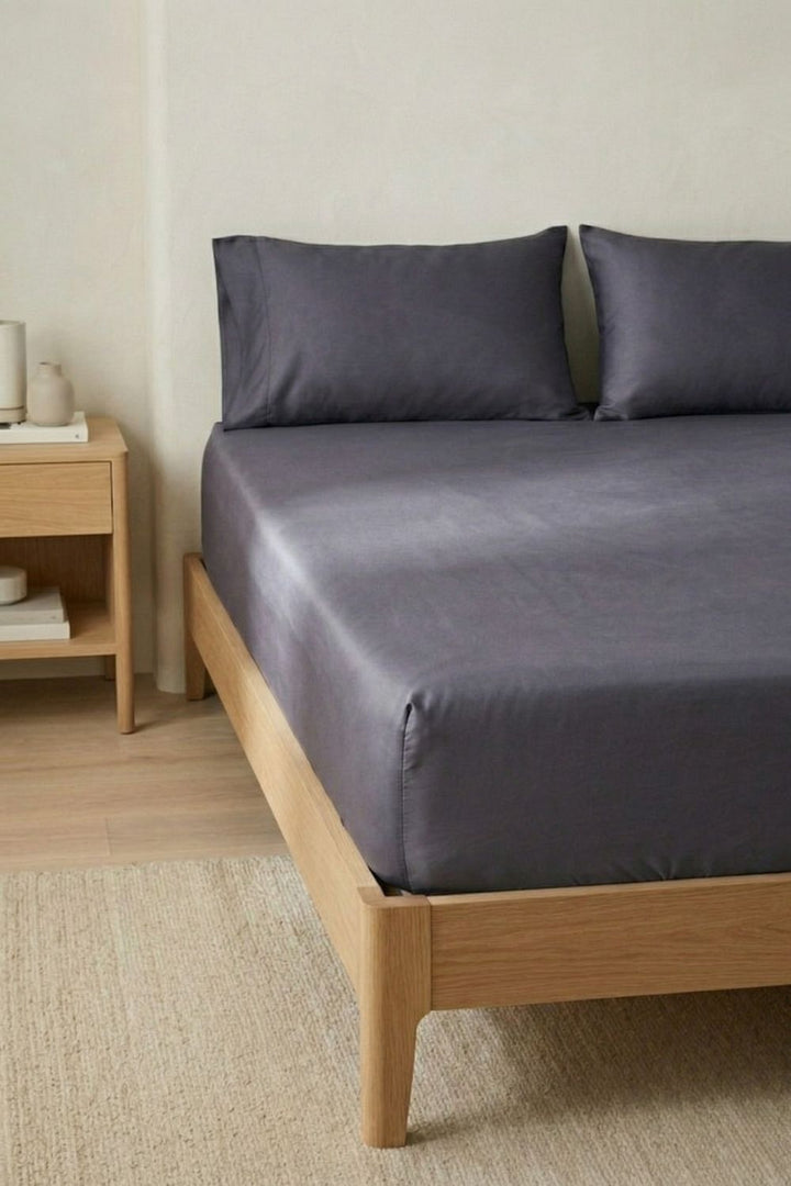 Bed with charcoal bedding and wooden frame in a room setting
