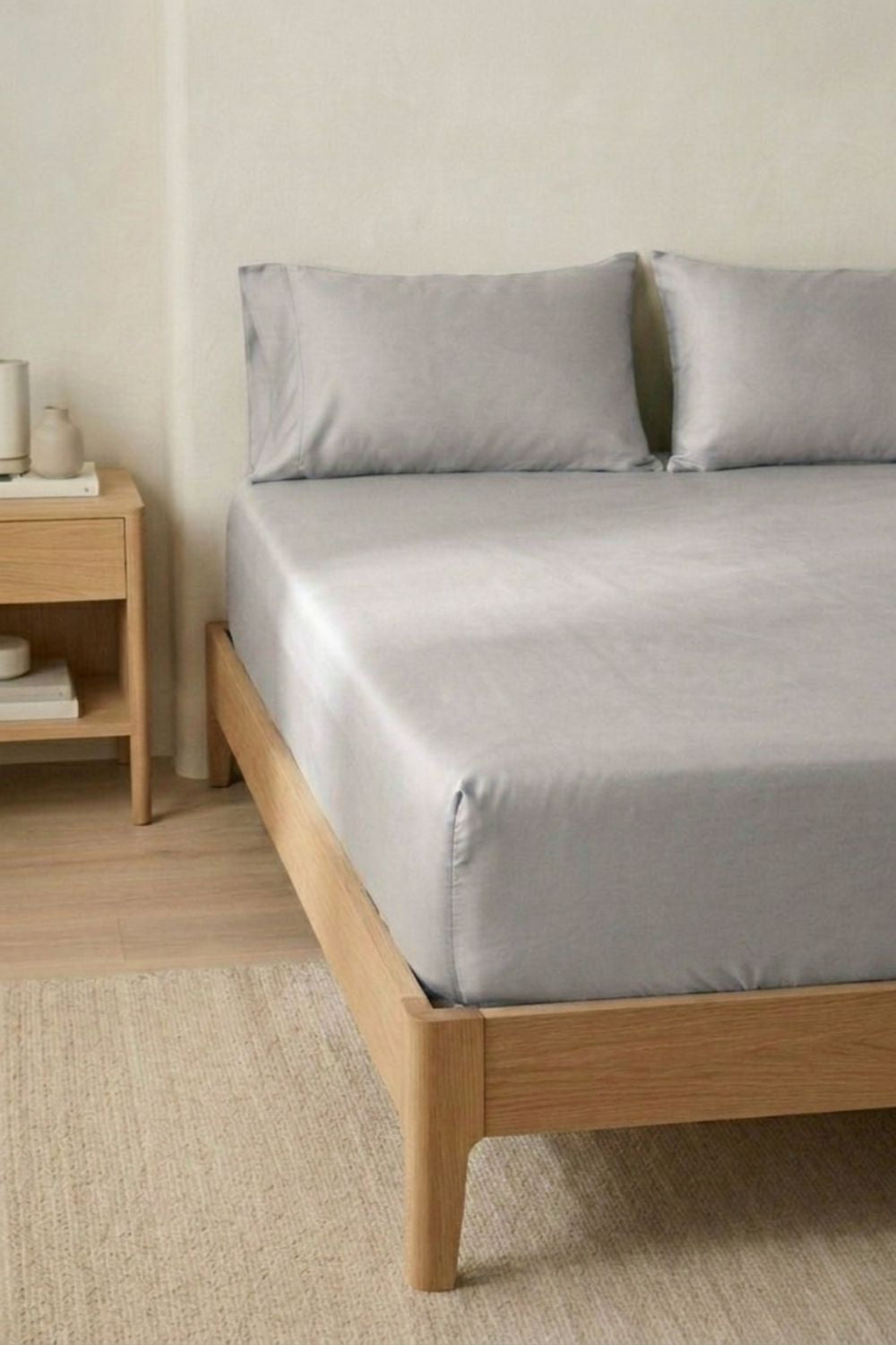 Bed with a taupe bamboo fitted bed sheet and pillows in a bedroom setting.