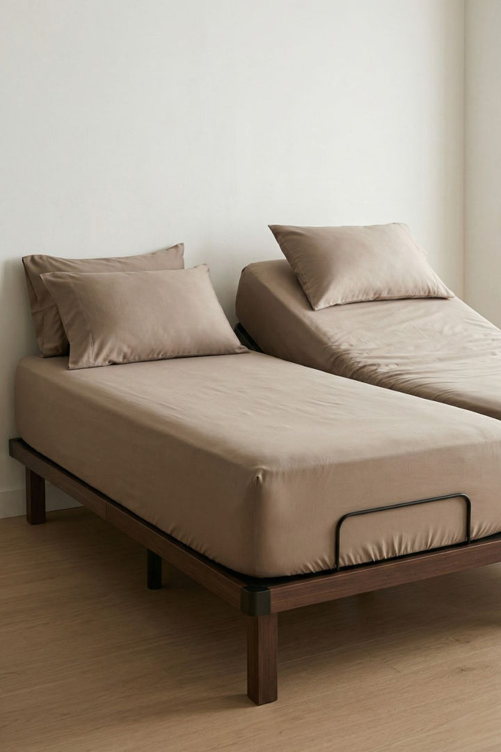 High-quality warm taupe sheets shown on an elevated adjustable bed base in a modern, neutral-toned bedroom.