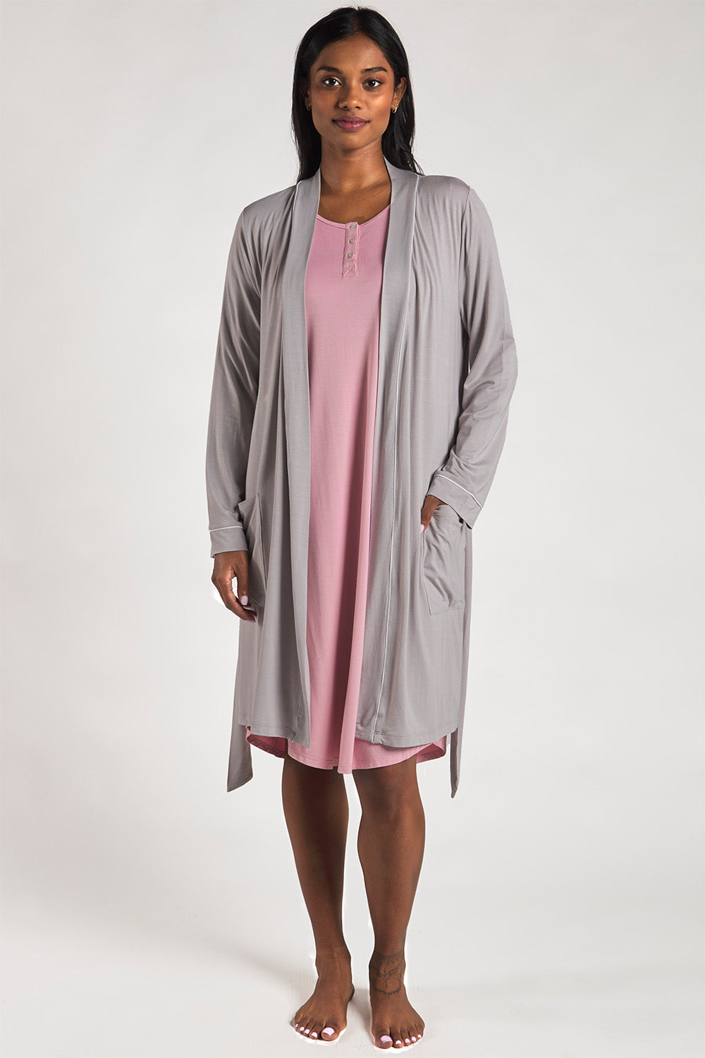 A woman wearing a sustainable bamboo sleep dress in Pink paired with an ultra-soft bamboo lounge robe in Ice Grey.