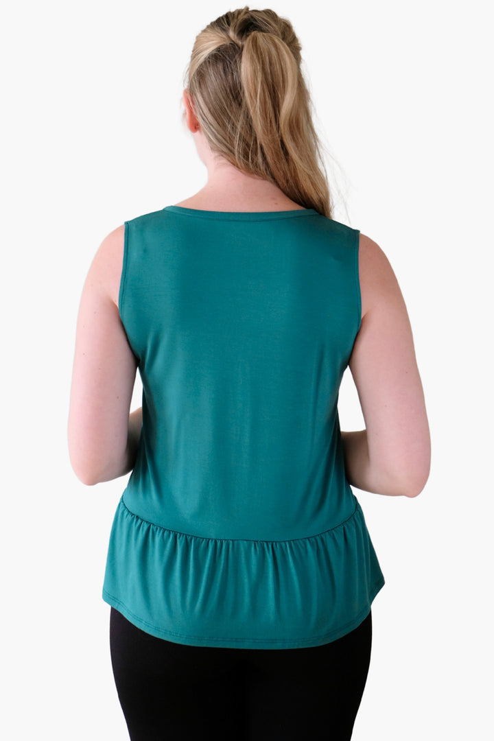 Woman wearing a teal sleeveless top with peplum details on the hem and a v-neck line