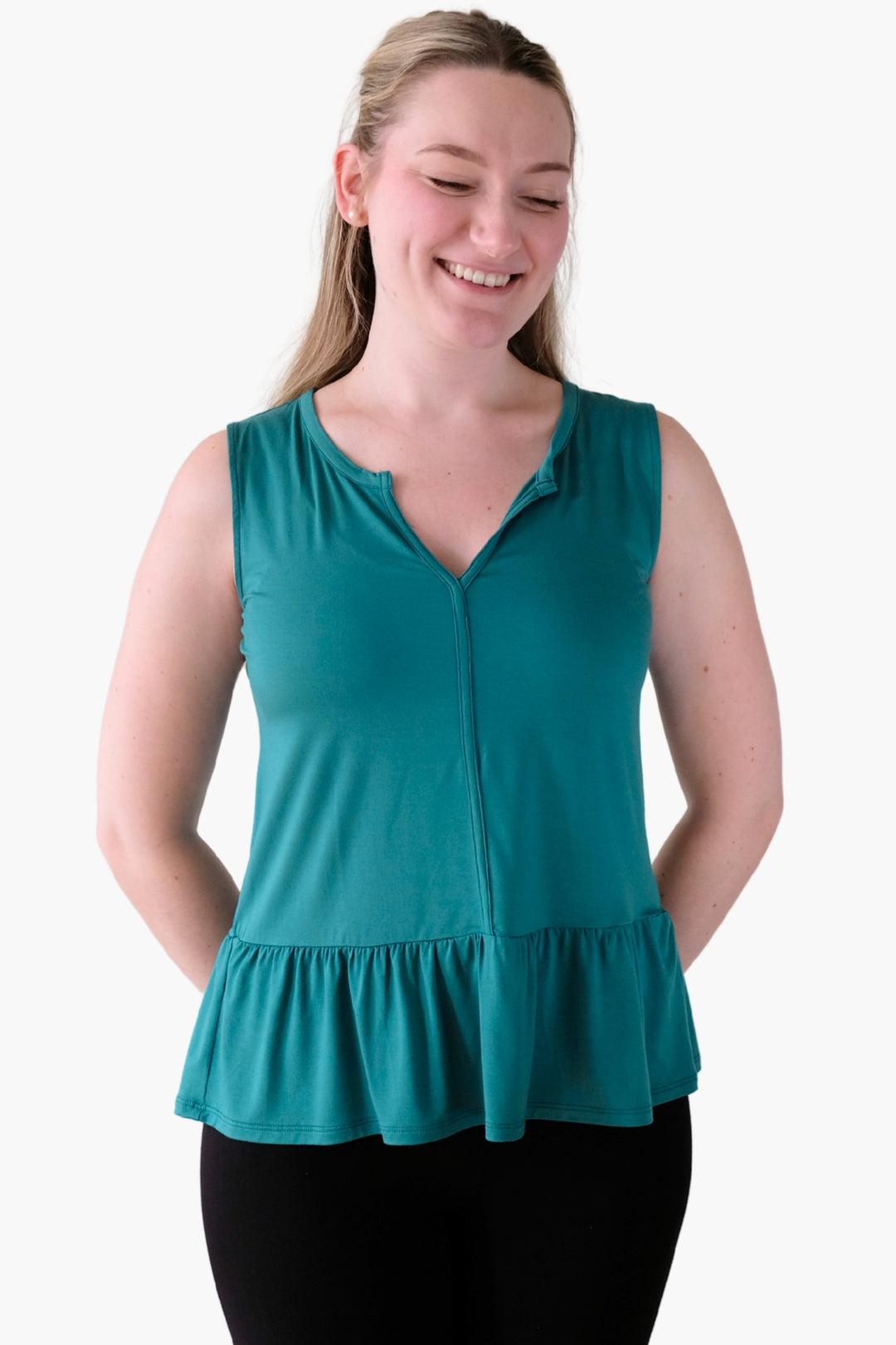 Woman wearing a teal sleeveless top with peplum details on the hem and a v-neck line