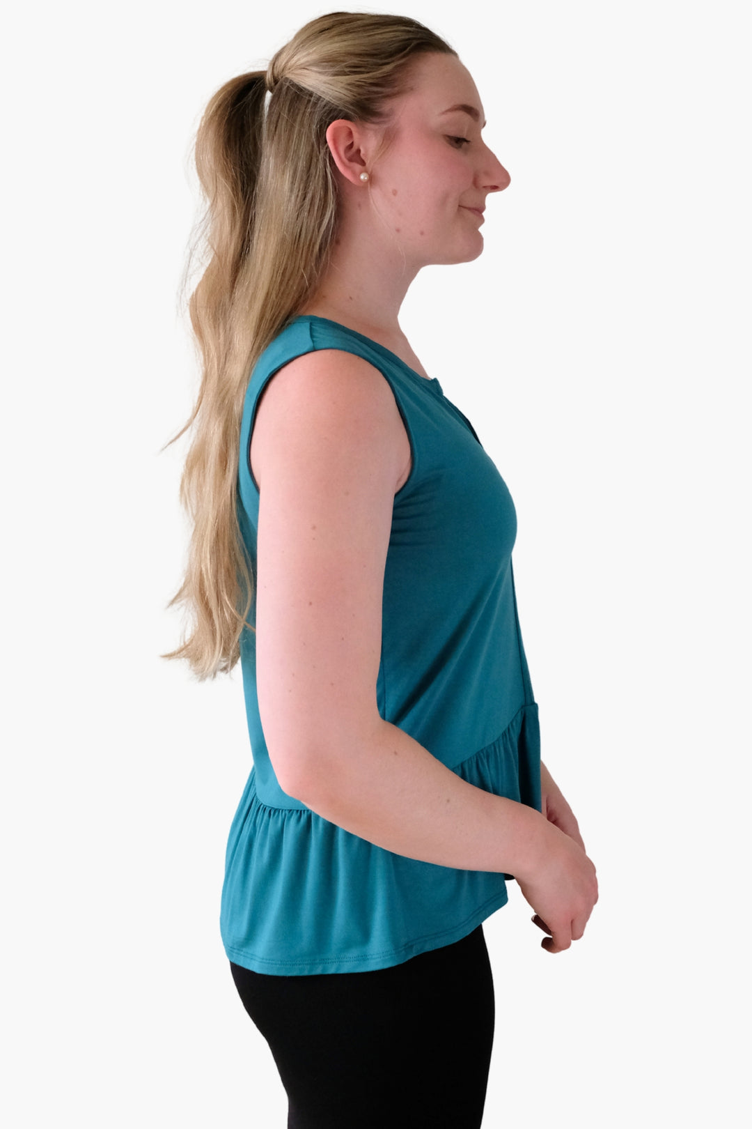 Woman wearing a teal sleeveless top with peplum details on the hem and a v-neck line