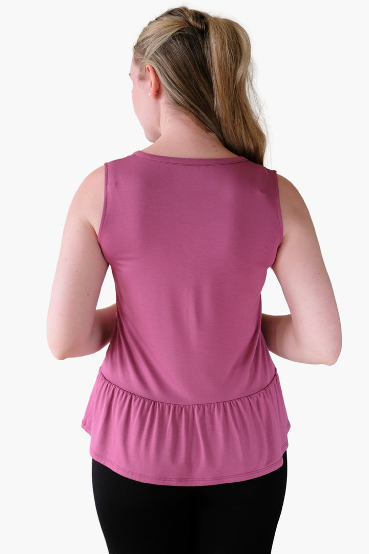 Woman wearing a pink sleeveless top on a white background with a peplum hem