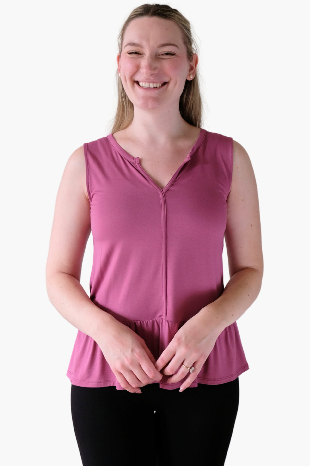 Woman wearing a pink sleeveless top on a white background with a peplum hem