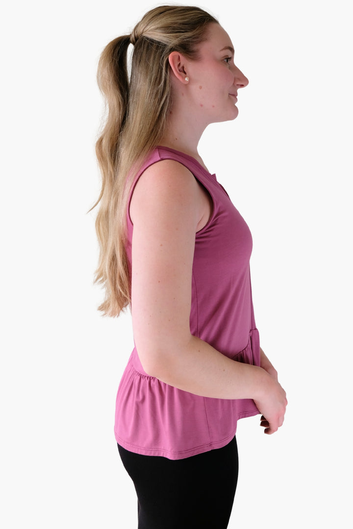 Woman wearing a pink sleeveless top on a white background with a peplum hem