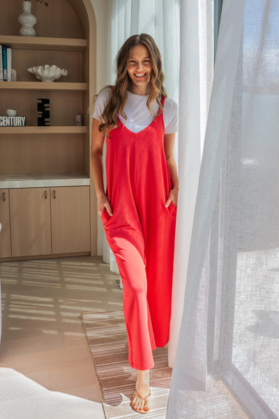 Model wearing a bamboo jumpsuit with wide legs in the color Melon by Terrera. Model is showing the front view of the jumpsuit paired with a white t-shirt underneath.