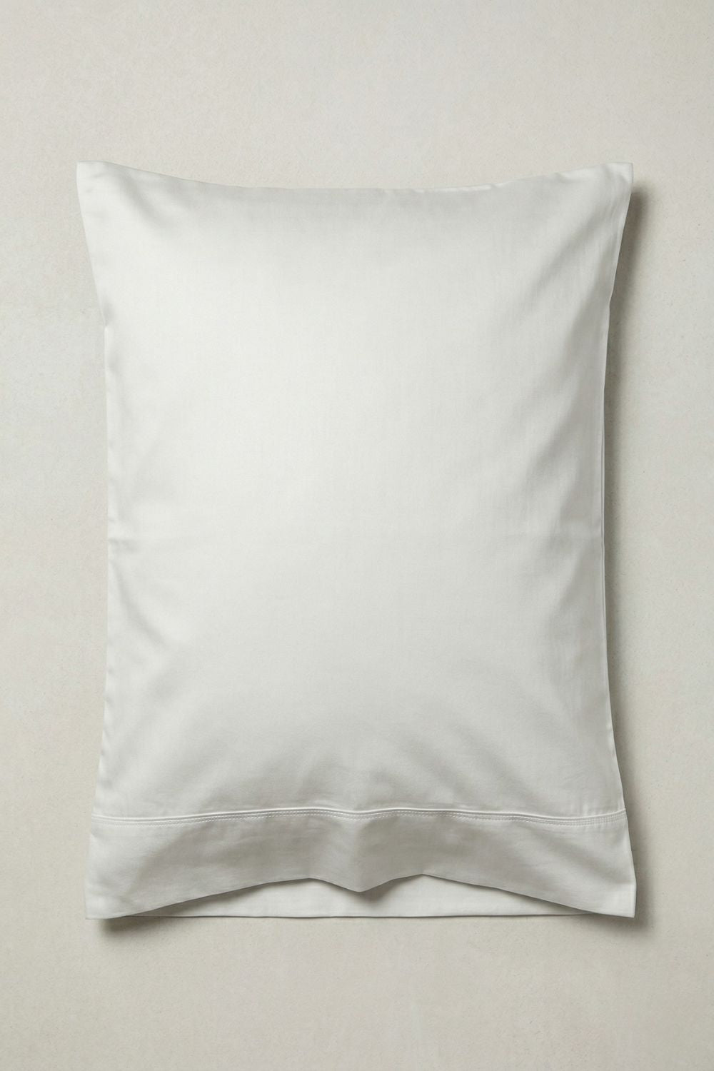 Warm white standard size pillow on a grey background
