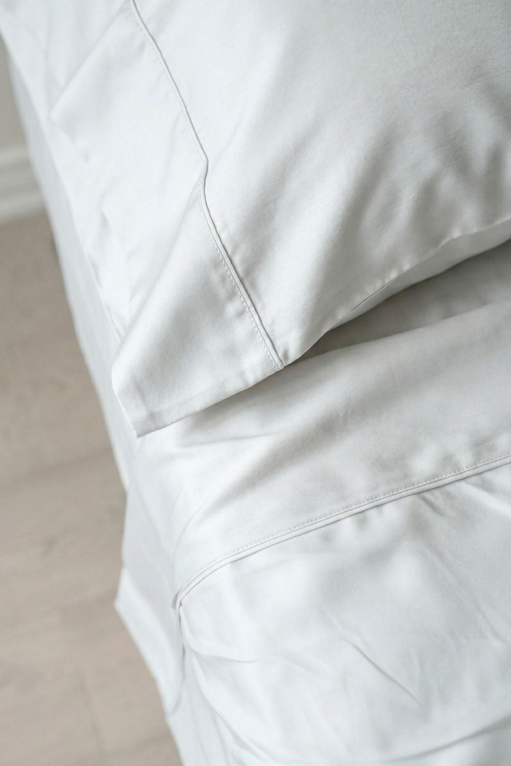 Close-up of white bamboo bedding with a soft texture on a neutral background