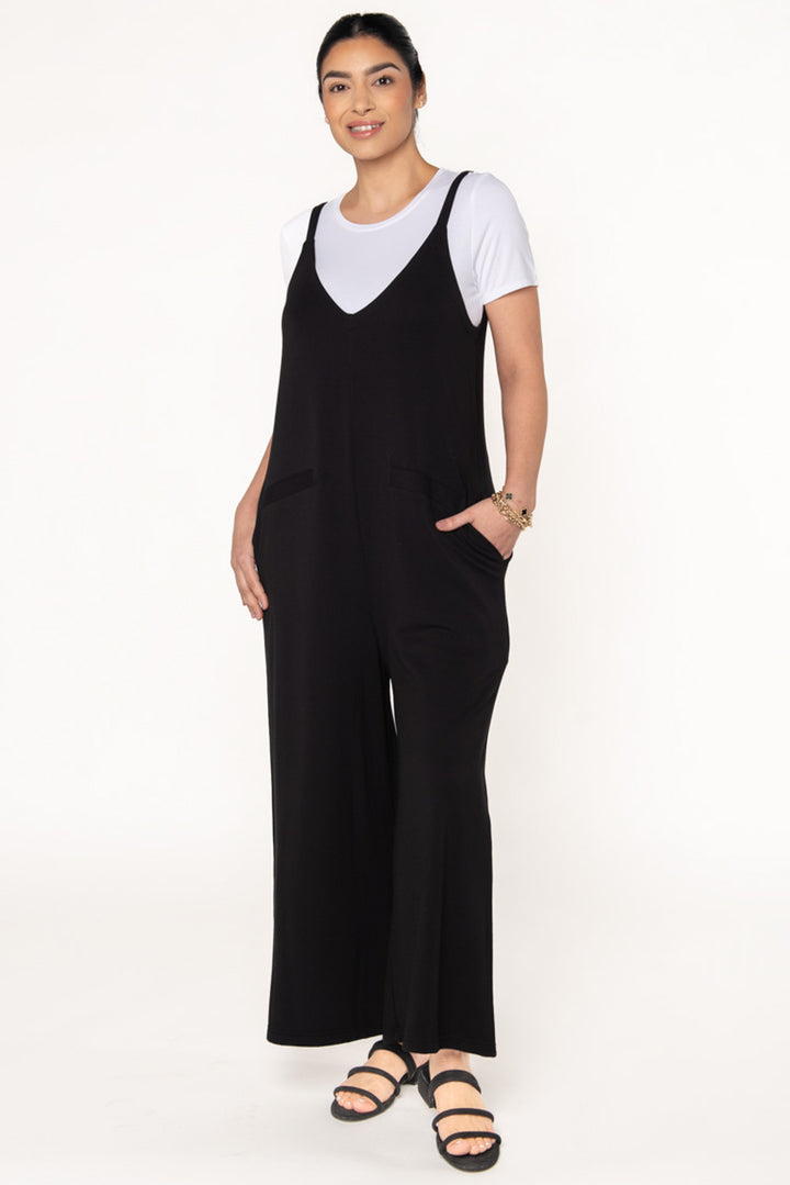 Model wearing a black bamboo jumpsuit by Terrera. Layered underneath the jumpsuit is a white t-shirt. 