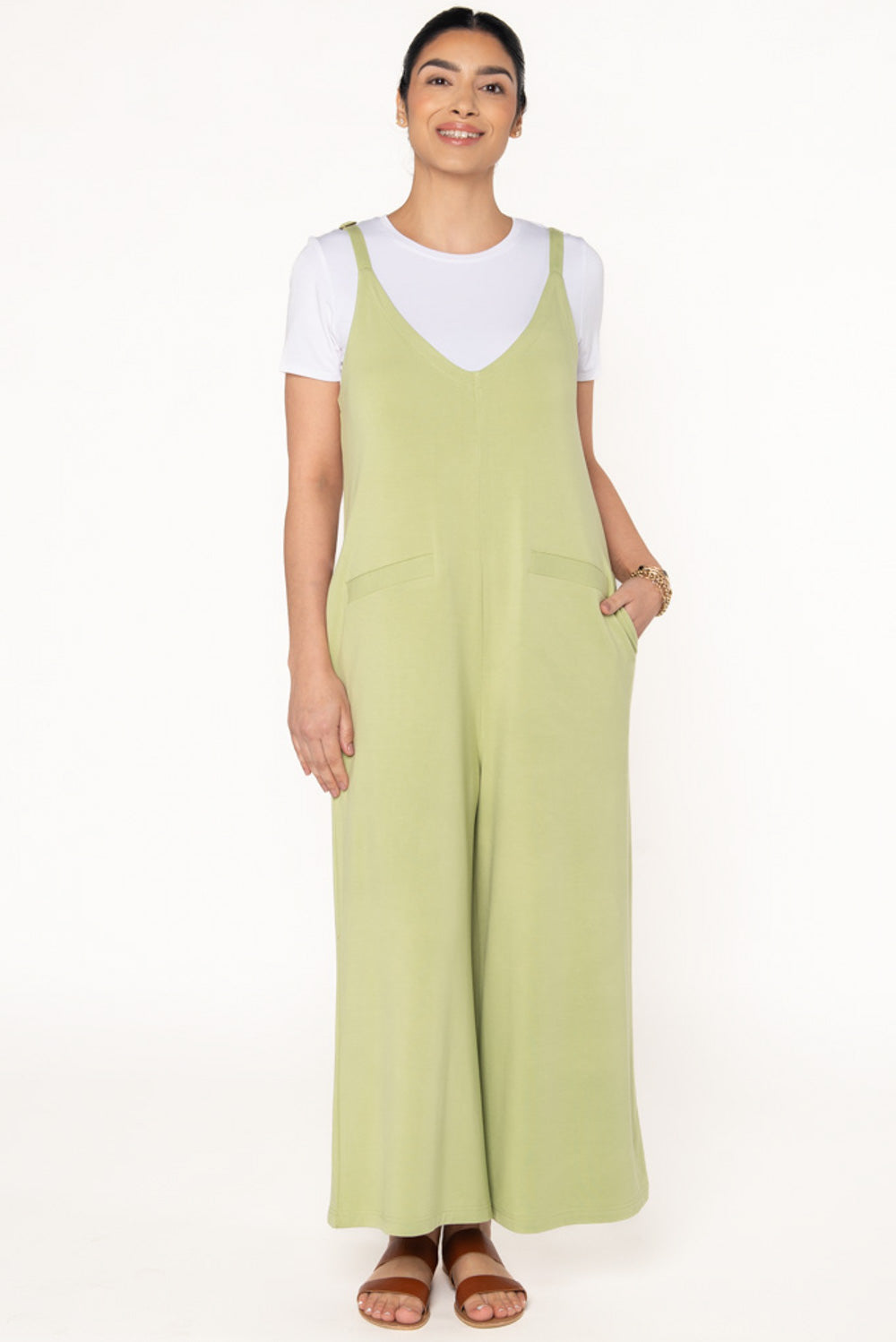 Model wearing a Citron green bamboo jumpsuit with wide legs, pockets, and adjustable thin straps. Layered underneath the jumpsuit is a white t-shirt. Model is showing the front view of the jumpsuit.