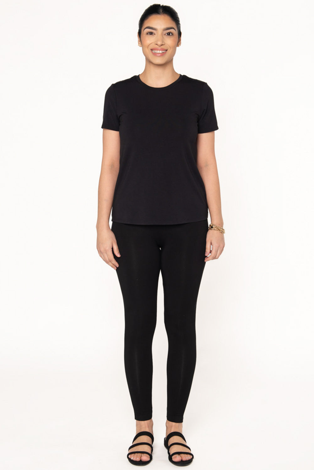 A model wearing a black bamboo short sleeve t-shirt with a crew neckline paired with black bamboo leggings and black sandals.