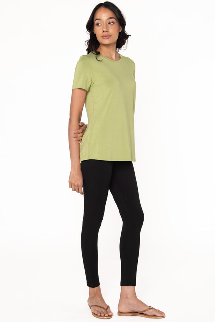 A model wearing a light green crewneck t-shirt with bamboo leggings and brown flip flops.