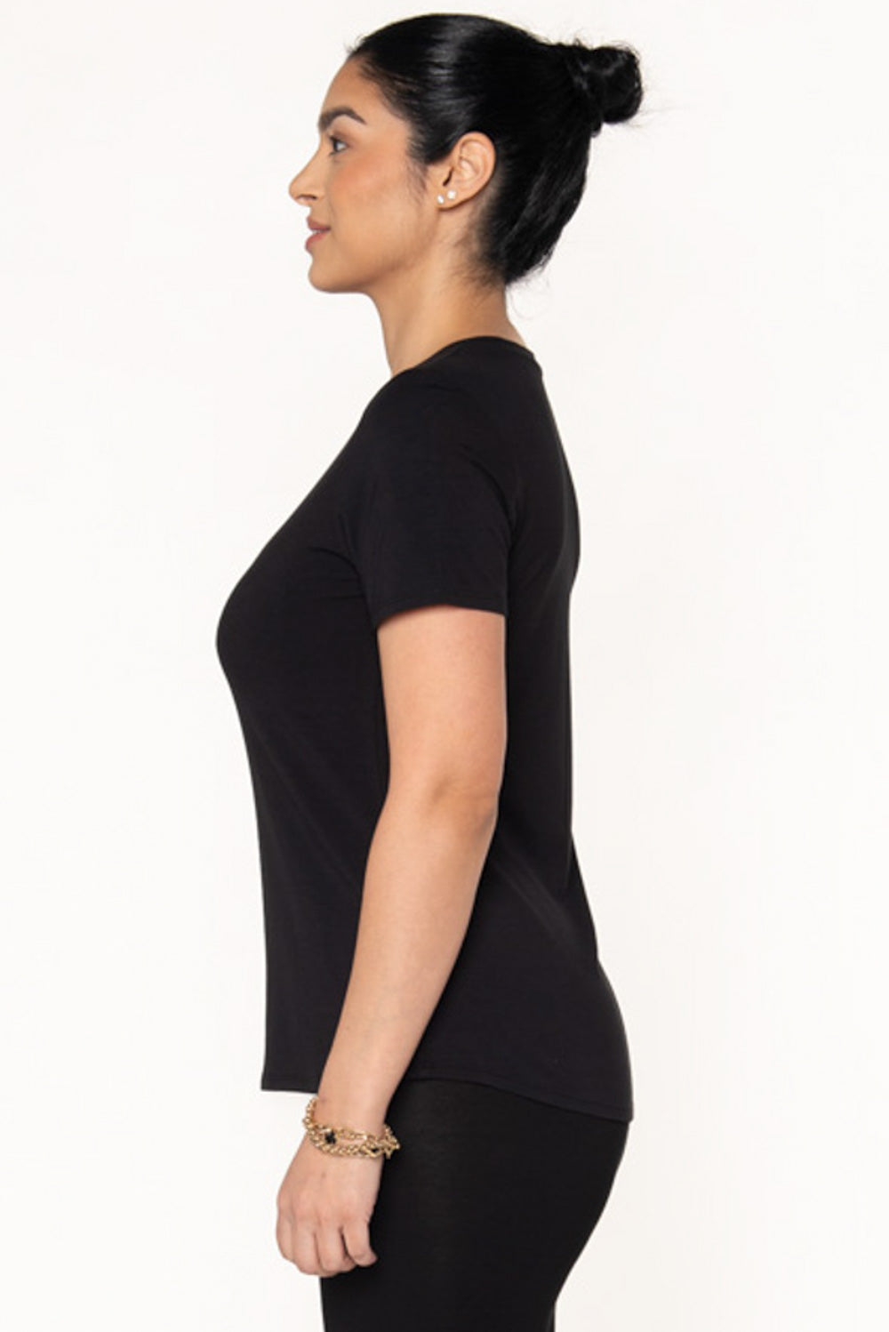 A model showing a black bamboo t-shirt with a crew neckline by Terrera. Model is showing the side view of the short sleeve t-shirt featuring a slight high low hemline.
