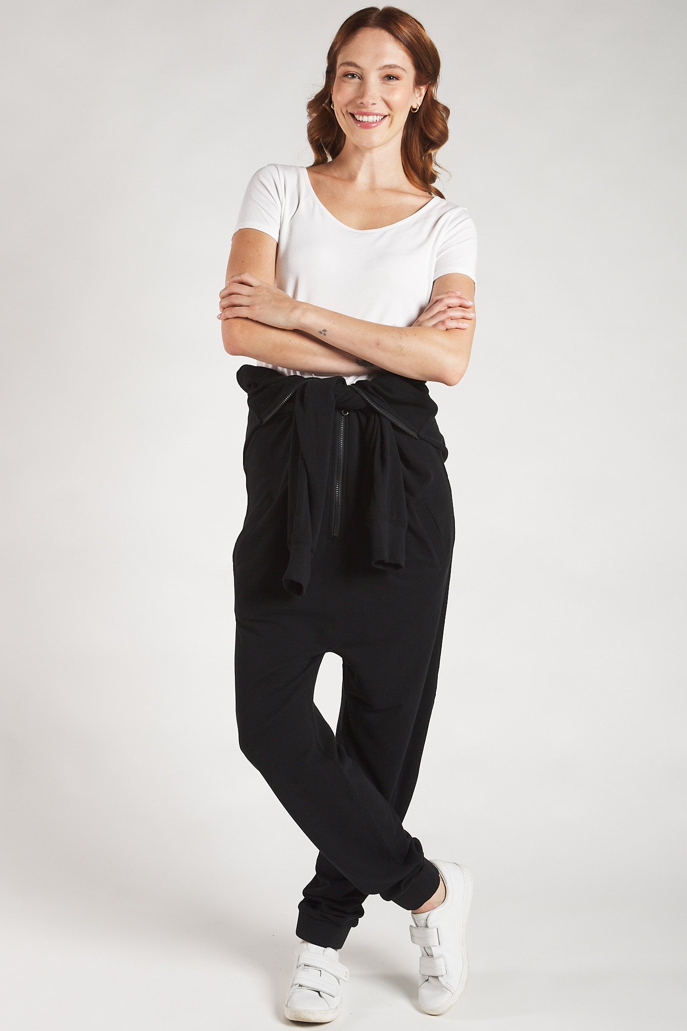 Women’s sustainable black lounge jumpsuit tied at the waist styled with a white t–shirt. 