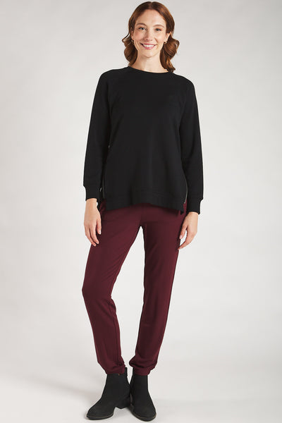 Woman styling a Terrera black sweatshirt with cranberry leggings. 