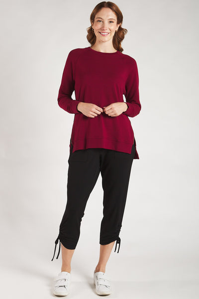 Woman styling a Terrera cranberry sweatshirt with black pants and white sneakers.