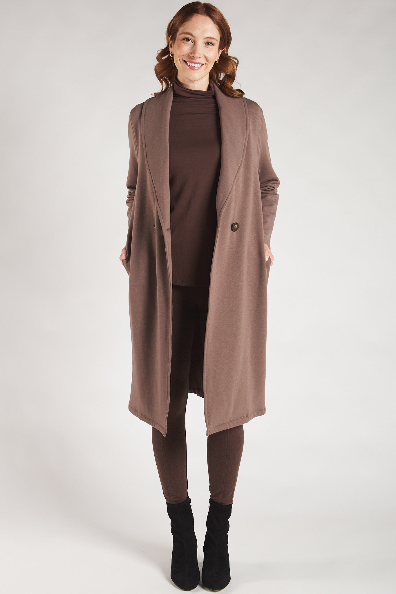 Woman styling a brown long sleeve turtleneck top with a brown jacket from Terrera.