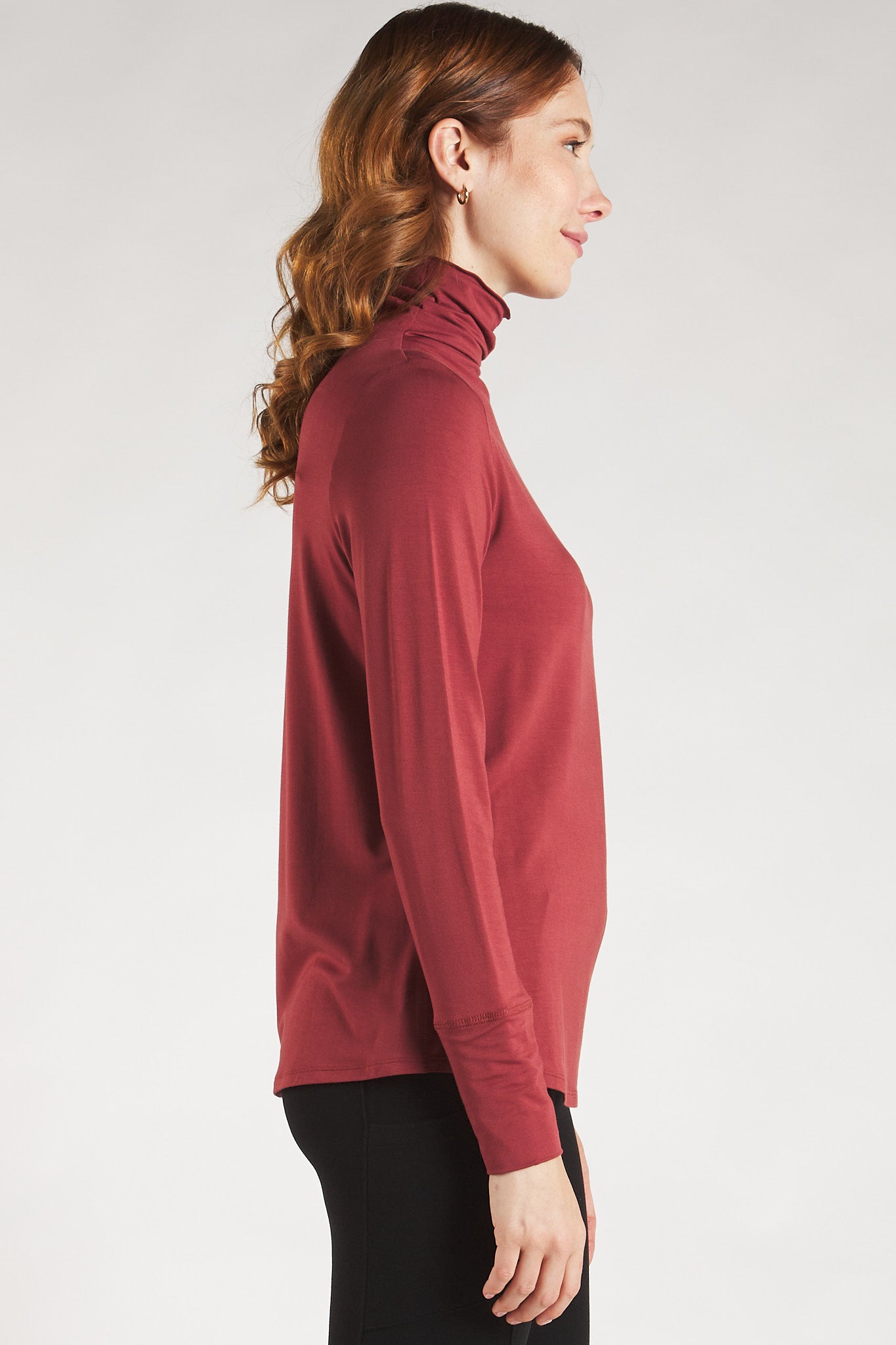 Side view of woman styling a Rosewood long sleeve turtleneck top by Terrera.