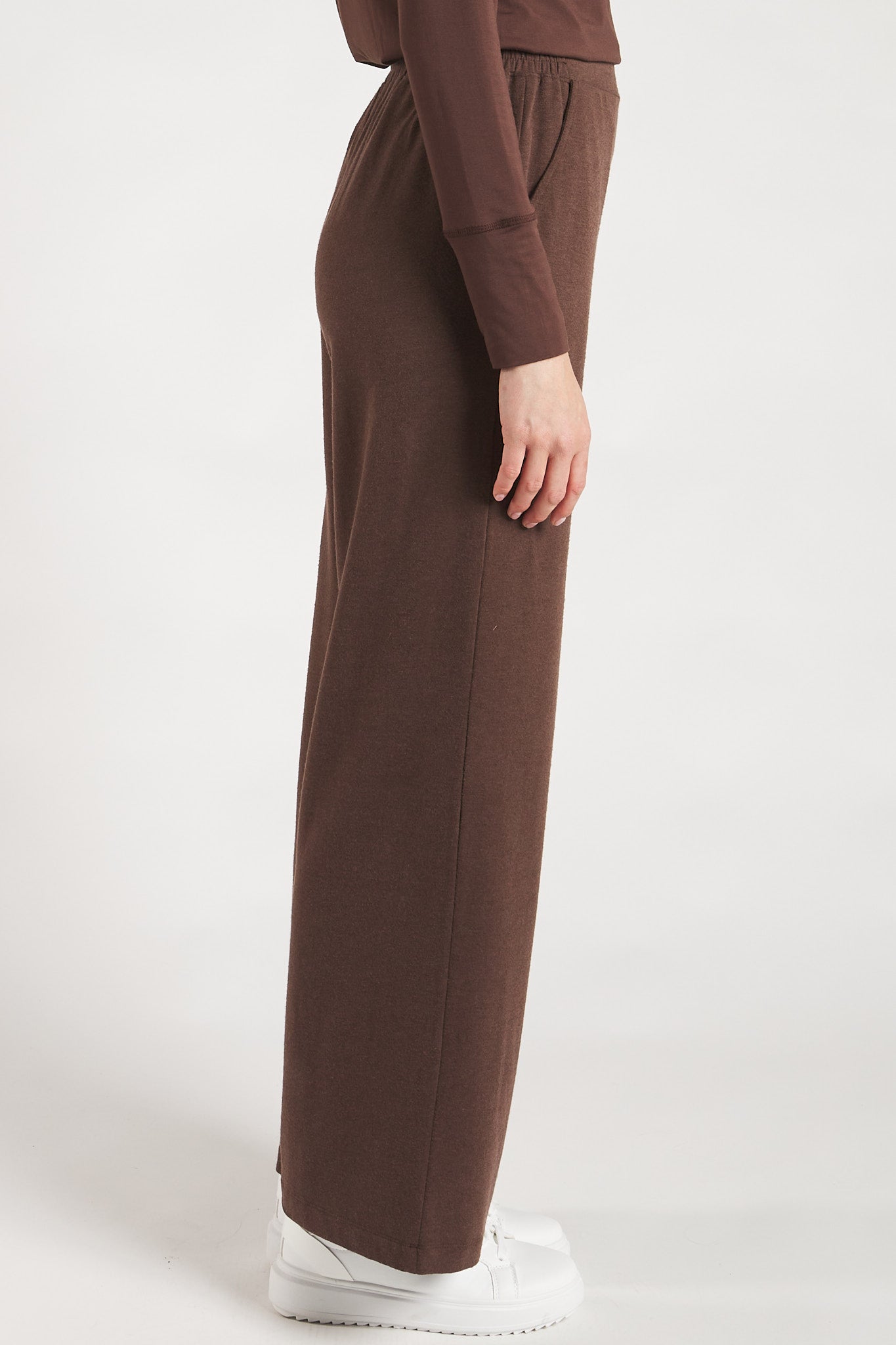 Side view of a woman styling Coffee Bean wide leg pants made from sustainable bamboo. 