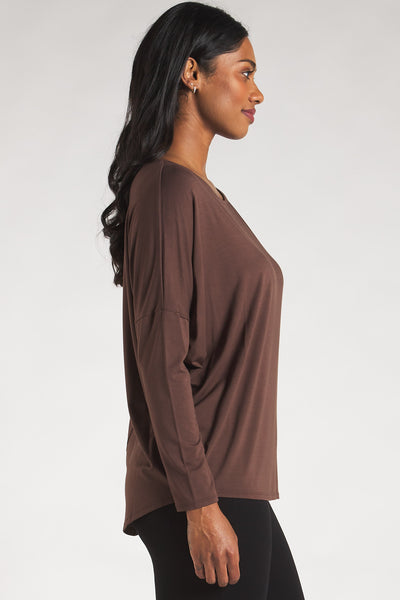 Side view of a woman styling a dark brown long sleeve top by Terrera. 
