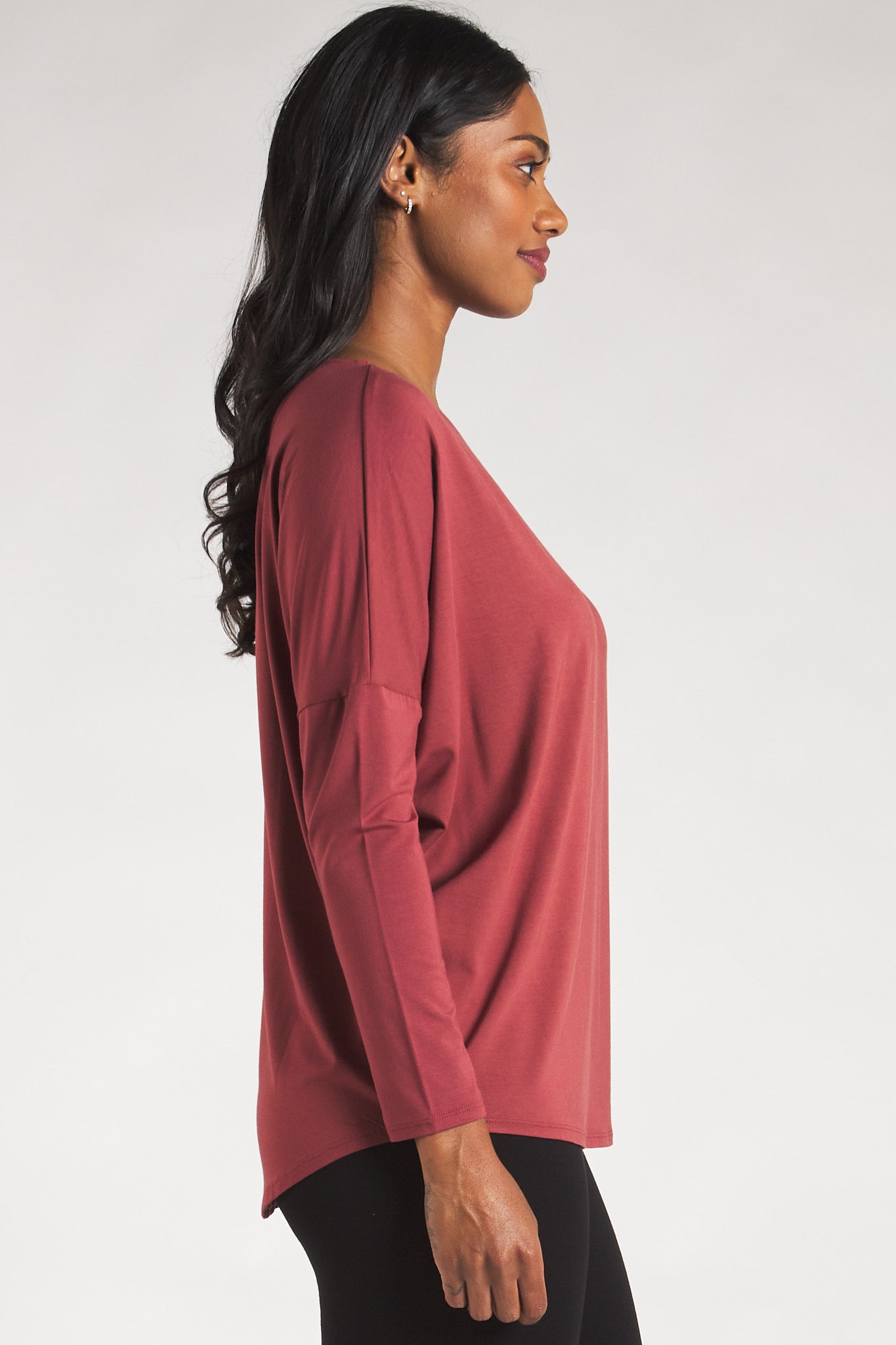 Side view of a woman styling a Rosewood long sleeve top by Terrera.