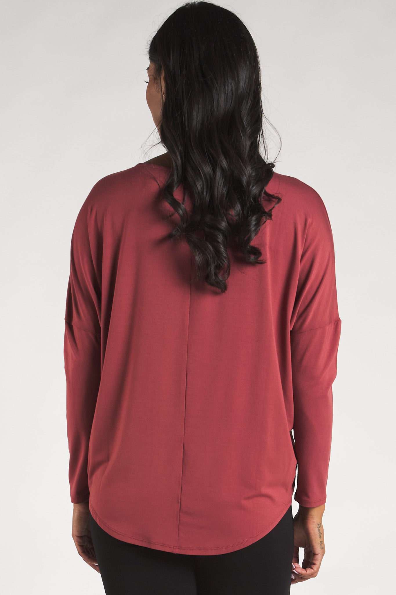 Back view of a woman styling a Rosewood long sleeve top by Terrera.